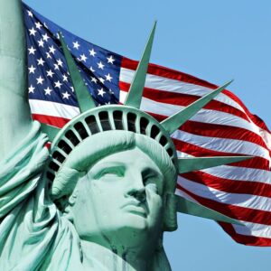 American flag waves behind the Statue of Liberty.