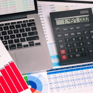 Traditional calculator & laptop atop data sheets.